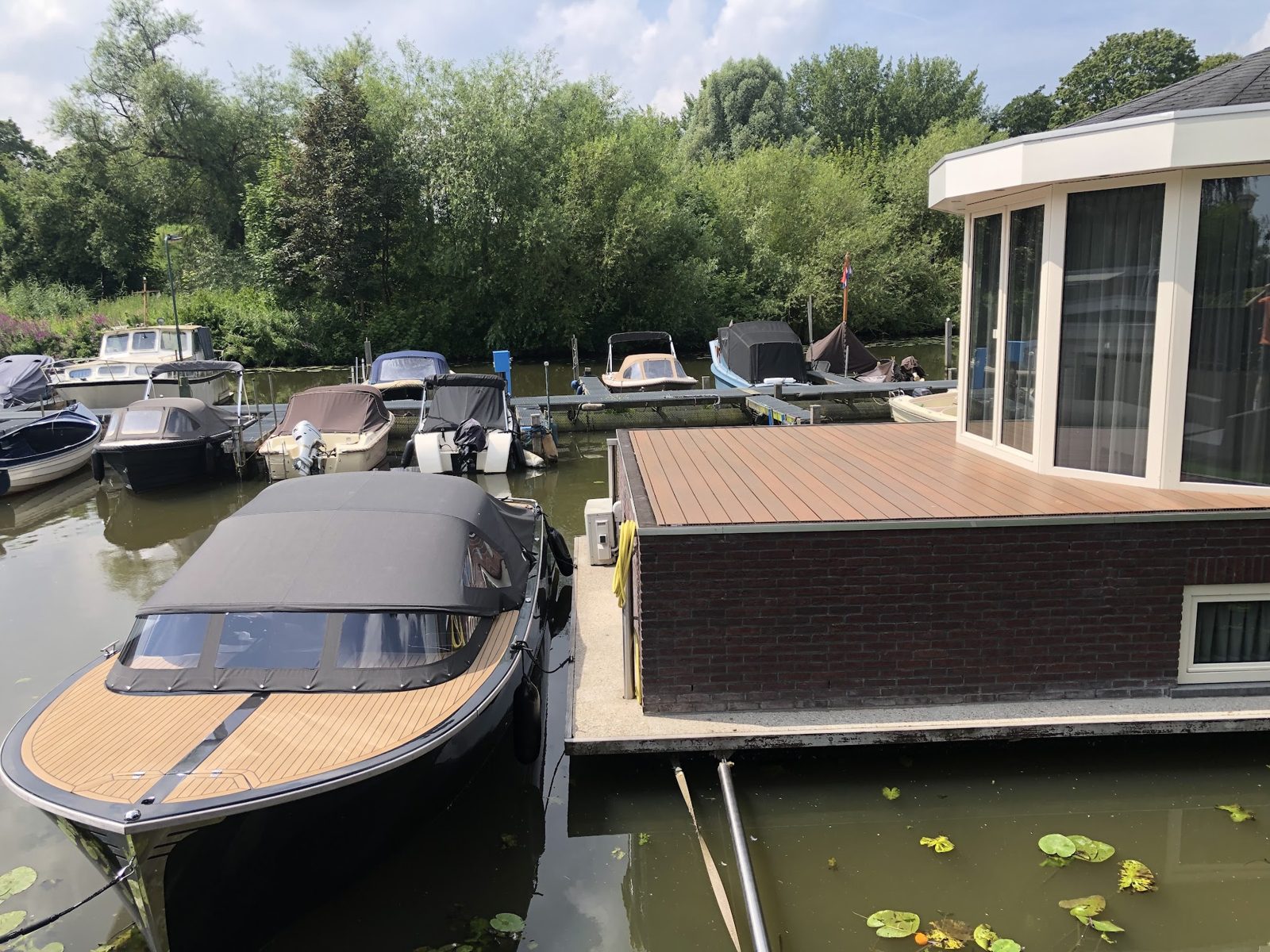 Houten terras aan het water naast een steiger met boten