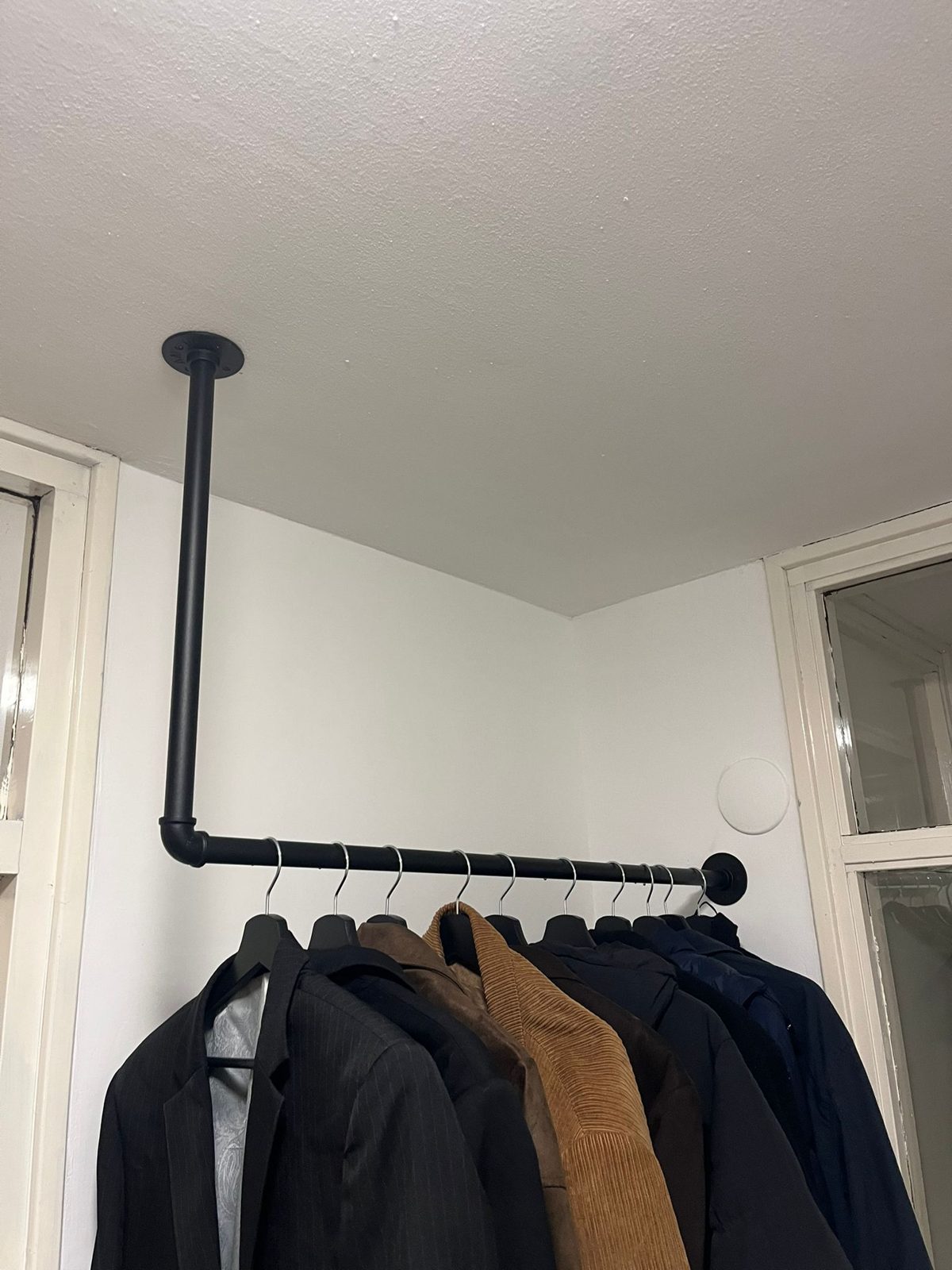 Zwarte buizen kledingrek aan het plafond bevestigd